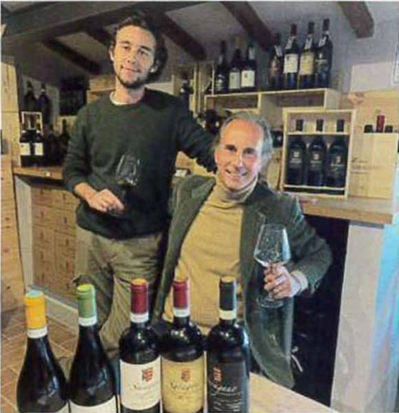 Due uomini sorridenti con calici di vino in una vendita di vino.